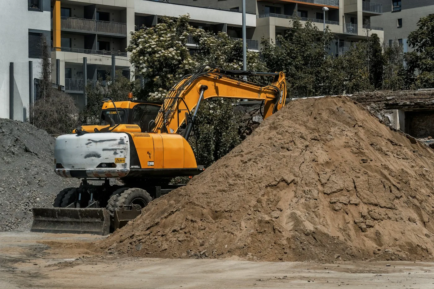 Excavator digging beside a soil stockpile